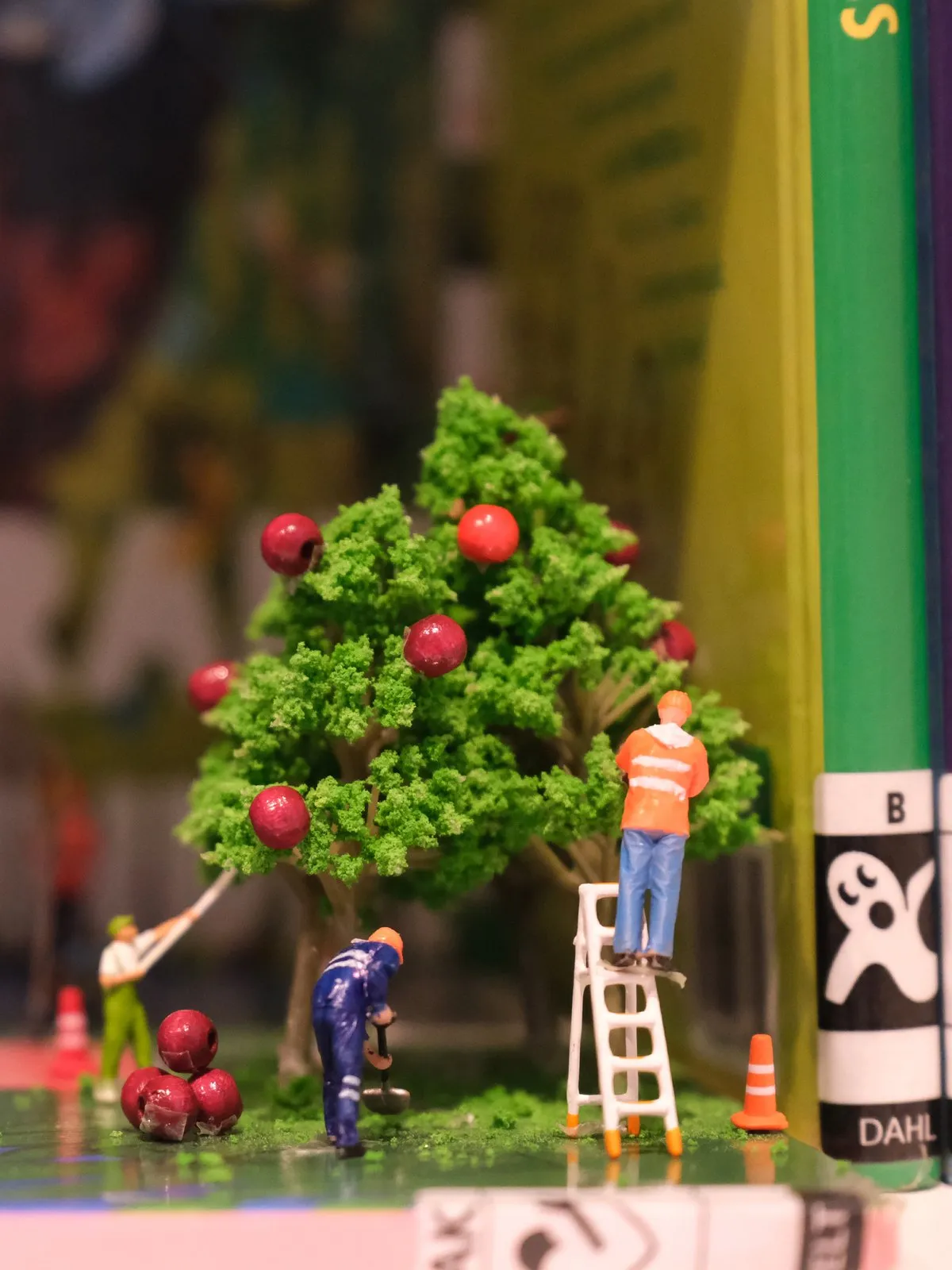 Miniatuurwerkers plukken appels uit een boompje op een boekenplank