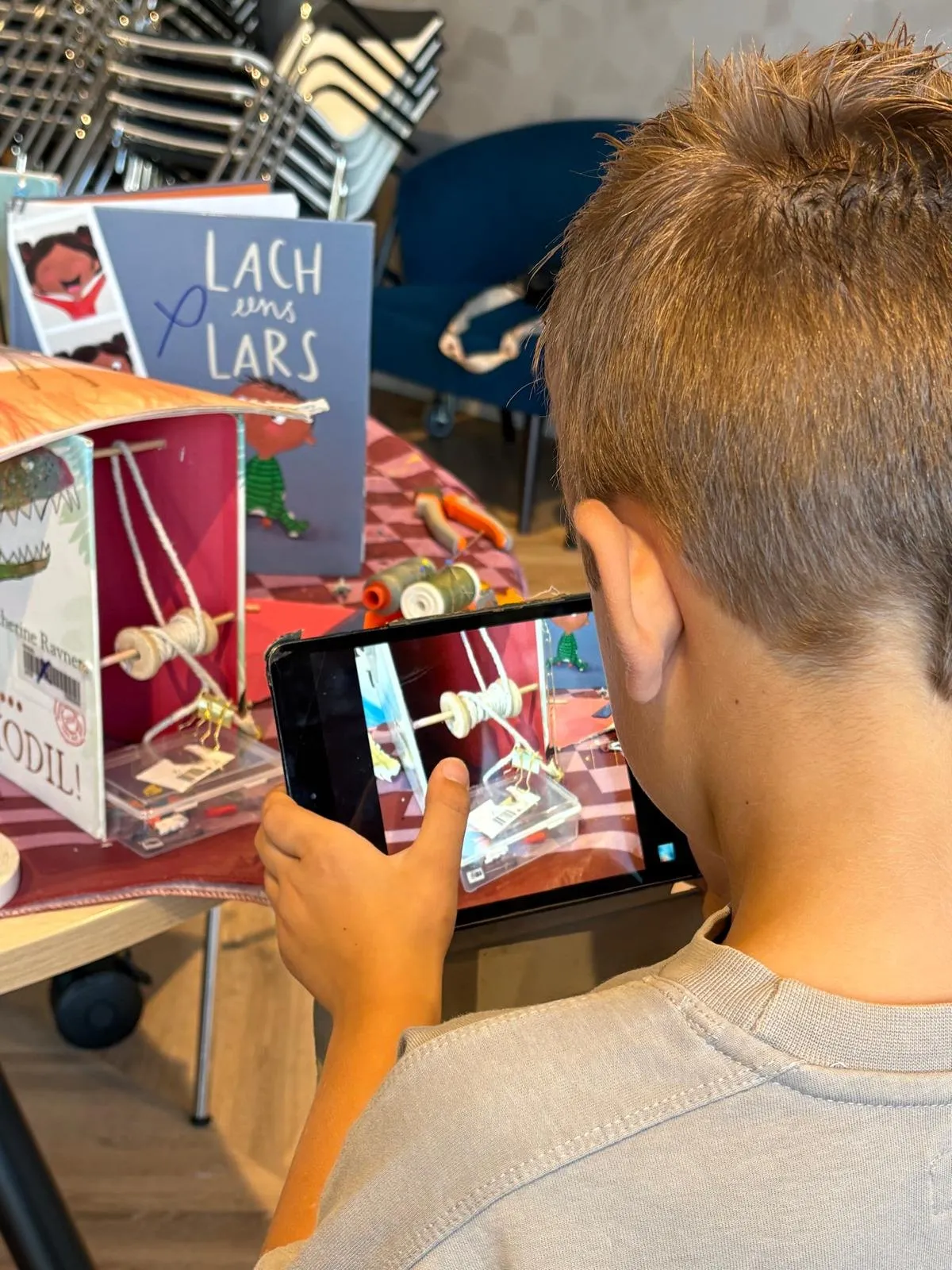 Een jongen fotografeert zijn scène met een tablet