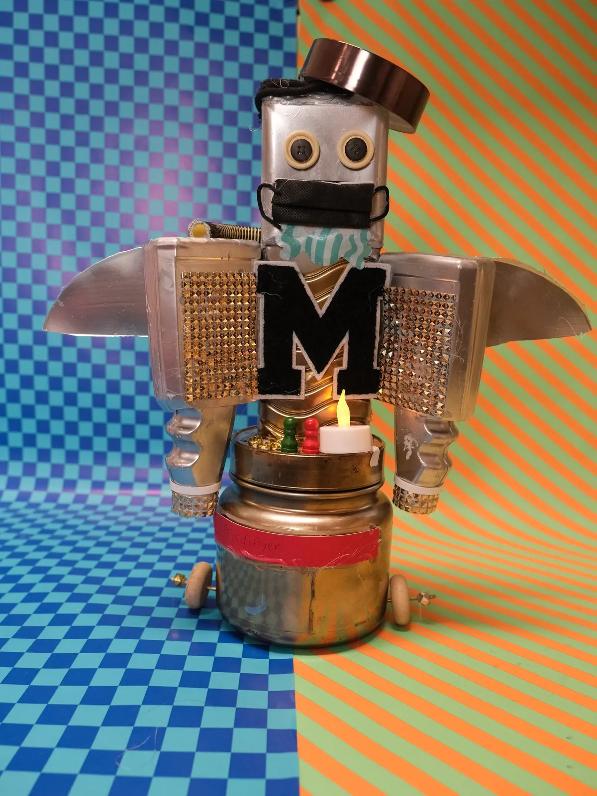 Een robot met mondkapje en een grote M op zijn borst