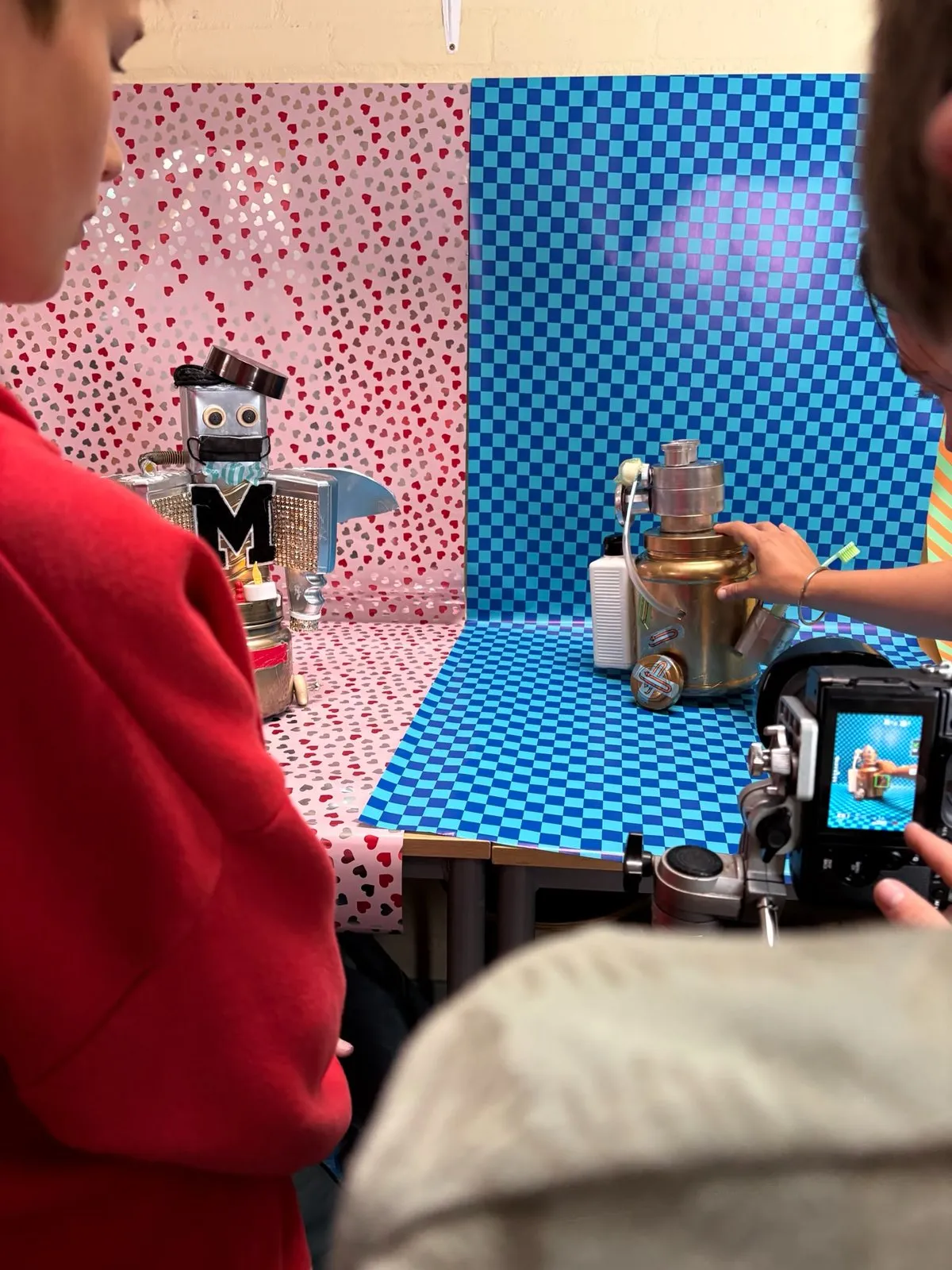 Een leerling in het rood fotografeert zijn robot op de set