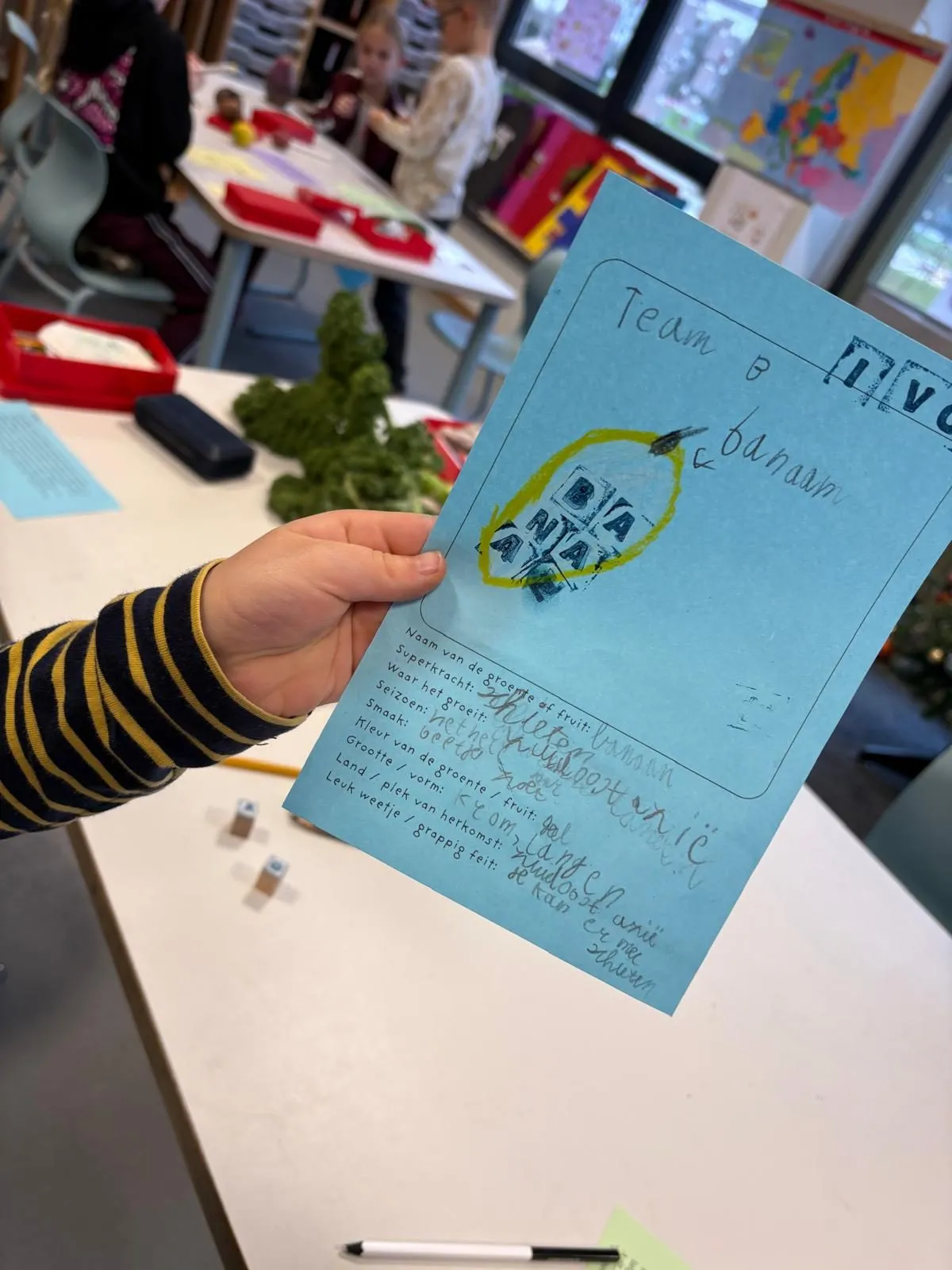 Een leerling houdt het blauwe paspoort van haar held omhoog